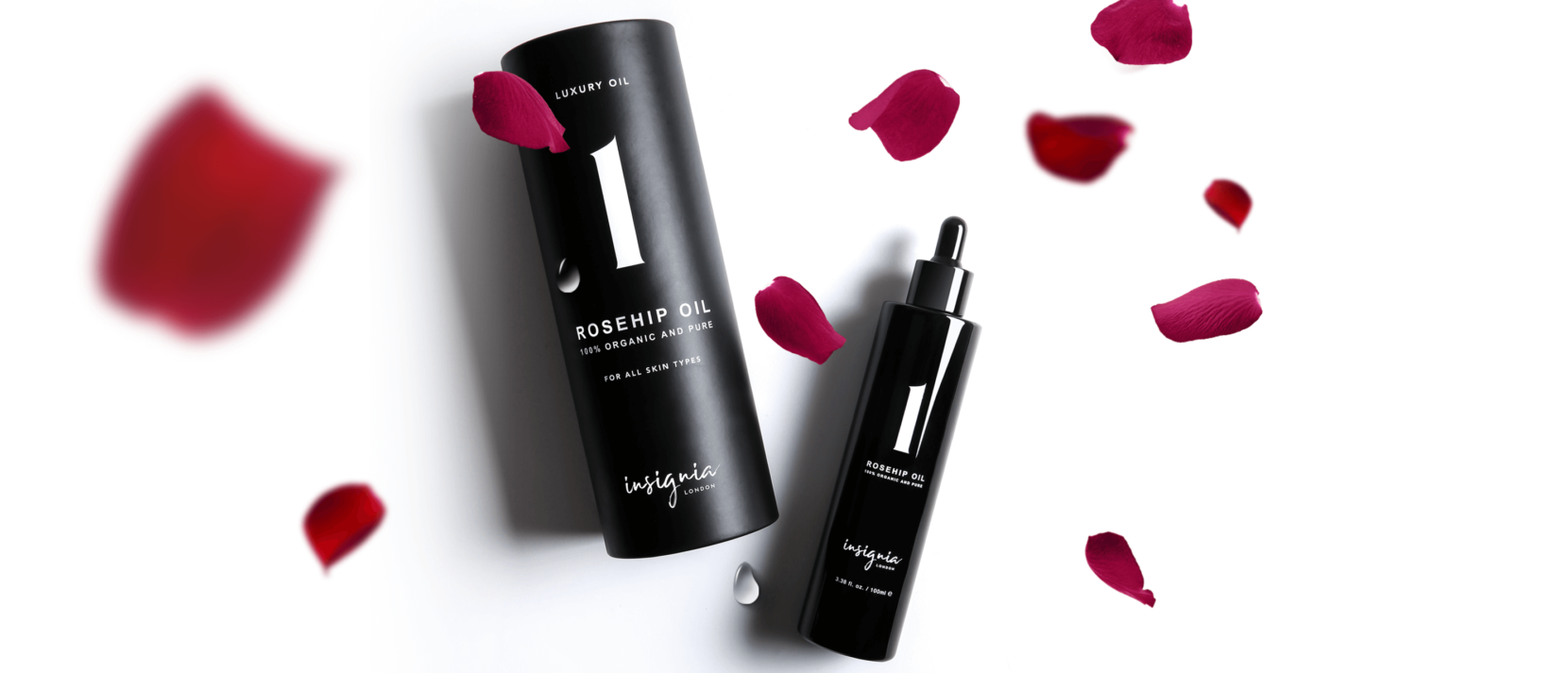 Insignia London No. 1 Luxury Rosehip Oil 30ml and 100ml black bottles surrounded by red rose petals on white background.