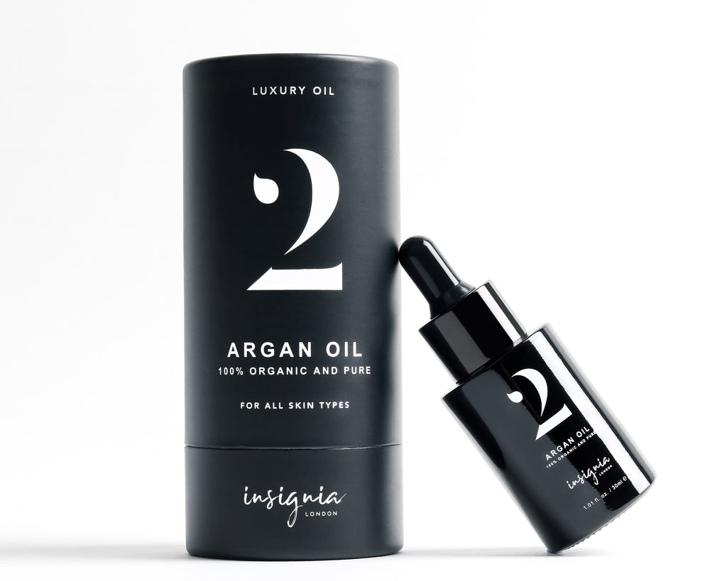 Insignia London No. 2 Luxury Argan Oil 30ml black glass bottle leaning against box on white background.